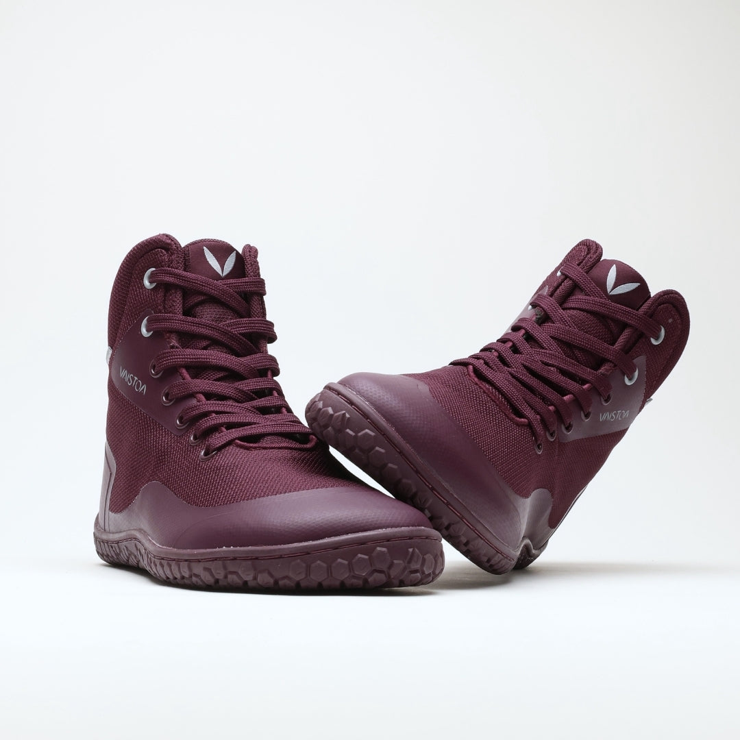 Vaistoa Tuohi 2 barefoot light hiking shoes burgundy – one shoe standing and the other resting against its shaft on its heel, with the outsole angled toward the camera