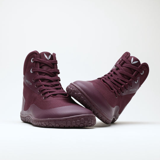 Vaistoa Tuohi 2 barefoot light hiking shoes burgundy – one shoe standing and the other resting against its shaft on its heel, with the outsole angled toward the camera