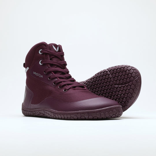 Vaistoa Tuohi 2 barefoot light hiking shoes burgundy – one shoe standing and the forefoot of the other resting on top of its toe cap, the leaning shoe's full honeycomb outsole facing the camera