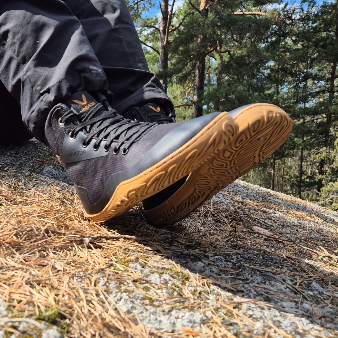 Vaistoa Tuohi barefoot trekking shoes black – lifestyle photo, spring, sitting on a rock in sunlight