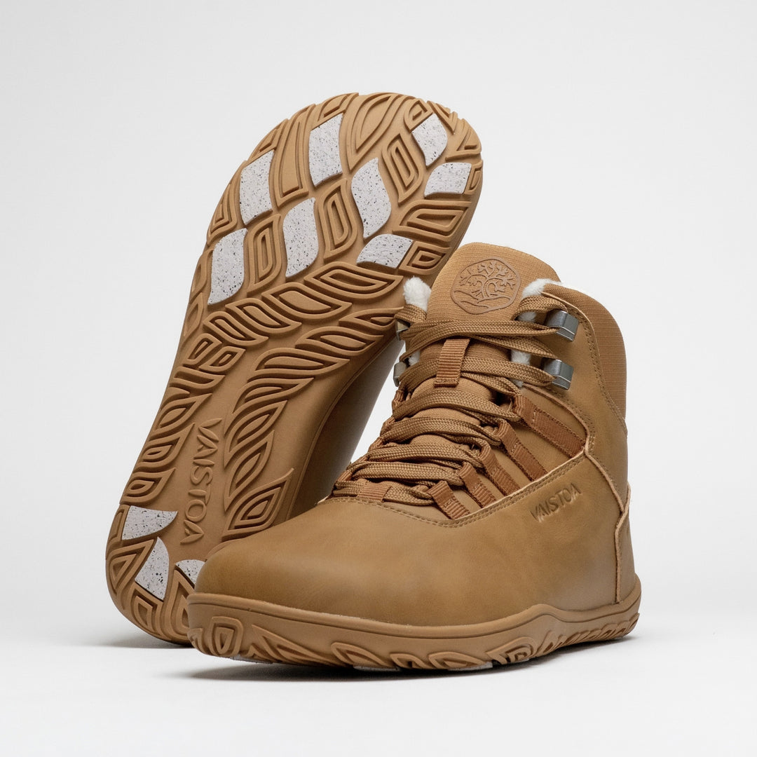 Vaistoa Uoma 4 winter barefoot trekking boots – pair with one shoe leaning against the shaft of the standing shoe with the outsole facing the camera, showing the Vaistoa logo and grip pads