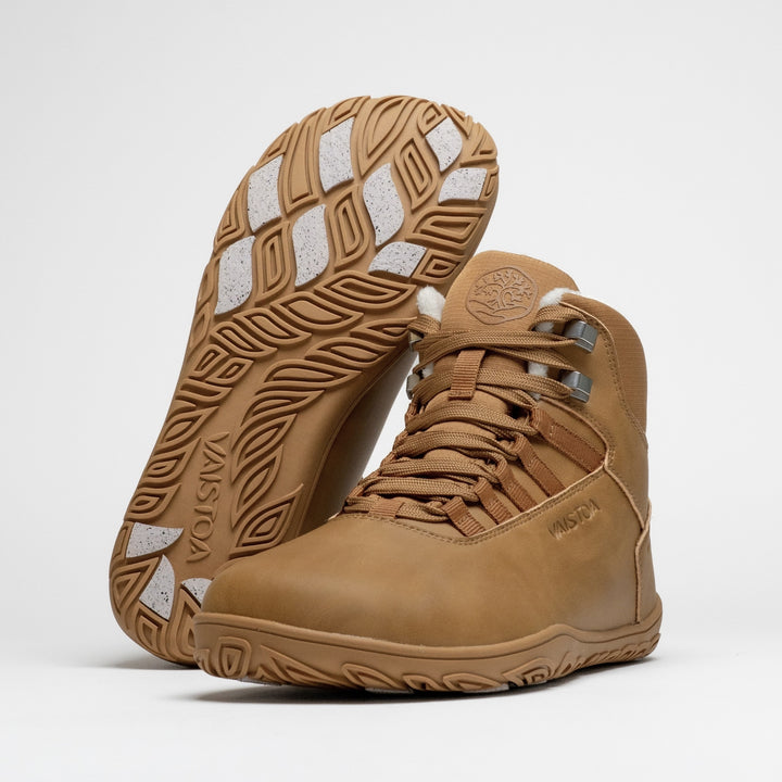 Vaistoa Uoma 4 winter barefoot trekking boots – pair with one shoe leaning against the shaft of the standing shoe with the outsole facing the camera, showing the Vaistoa logo and grip pads