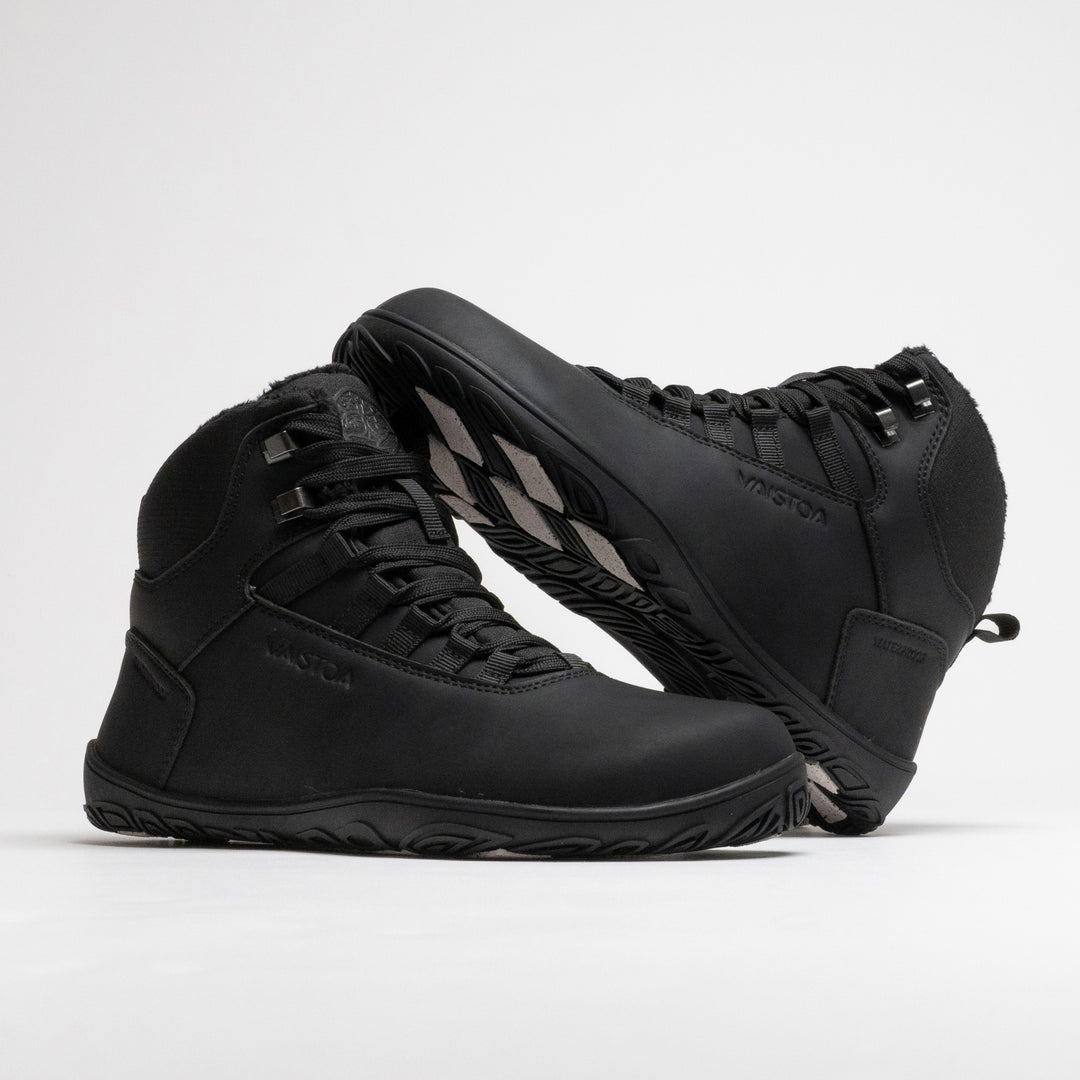 Vaistoa Uoma 4 winter barefoot trekking boots – pair with one shoe standing and the second leaning against its shaft with the toe pointing up, showing the side profile and the edge of the outsole