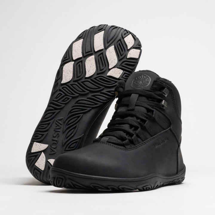 Vaistoa Uoma 4 winter barefoot trekking boots – pair with one shoe leaning against the shaft of the standing shoe with the outsole facing the camera, showing the Vaistoa logo and grip pads
