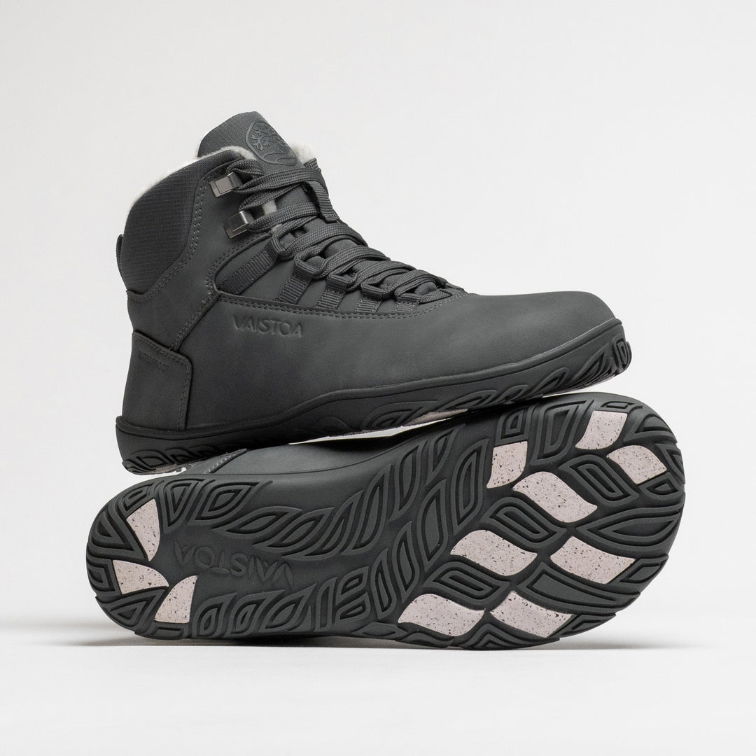 Vaistoa Uoma 4 winter barefoot trekking boots – one shoe standing on top of the other shoe's outsole, with the Vaistoa logo and grip pads visible on the outsole below