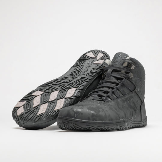 Vaistoa Uoma 4 winter barefoot trekking boots – pair with water droplets on the surface, one shoe lying with the outsole and grip pads facing the camera and the other standing in front of it