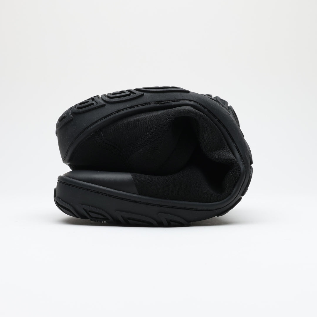 Black Vaistoa Vire barefoot shoe rolled up against a light background. The thin, flexible outsole and soft, sock-like construction are clearly visible, demonstrating the shoe’s flexibility.